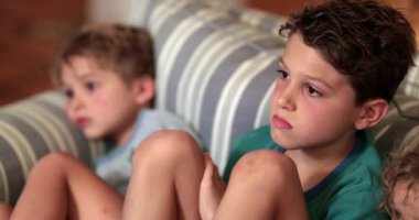 Çocuklar oturma odasında televizyon izliyor.