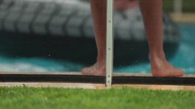 Havuzun kenarındaki çocuk bacakları. Çocuk havuz kenarında durup ağır çekimde suya atlıyor.