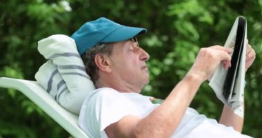 Authentic real life senior man reading traditional newspaper outdoors