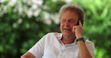 Senior man talking on phone casually. Older retired person speaking on smartphone