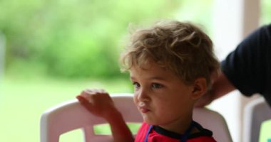 Baba, oğlunun saçlarını eliyle ovuyor. İçten bir aile anı. Tatlı çocuk yüzü.