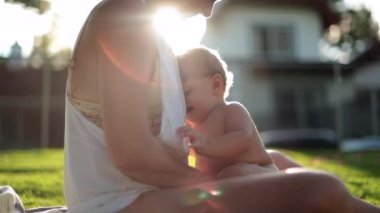 Mom and baby together in outdoor home garden with sunlight lens-flare