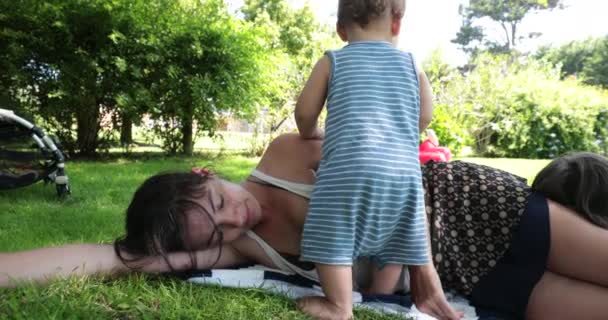 Mother Sleeping Grass Toddler Infant Wanting Attention Parent Taking Break — Stock Video