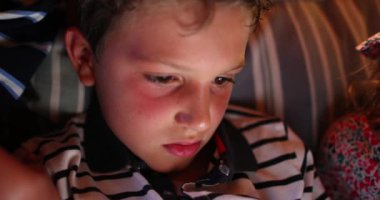 Geceleri ekranın önünde çocuk yüzü, mavi ışık parlıyor