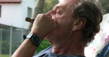 Yaşlı adam dışarıda puro içerek emekliliğin tadını çıkarıyor.