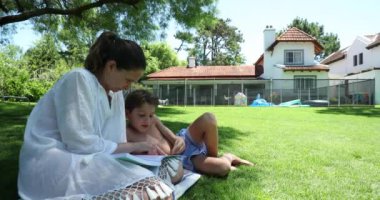 Ebeveyn çocuğuna dışarıda okumayı öğretiyor. Anne, çocuğun ödevlerine dışarıda yardım ediyor.