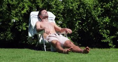 Arka bahçede 30 'lu yaşlarda bronzlaşan yakışıklı bir adam. Yaz günü bronzlaşma