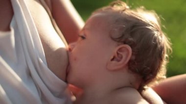 Mother breastfeeding one year old baby infant outdoors