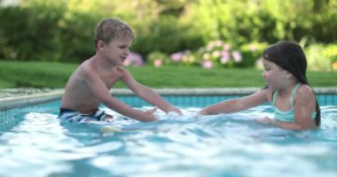 Çocuklar yüzme havuzunda birbirleriyle kavga ediyorlar. Çocuklar, kız ve erkek kardeşler kavga eder.