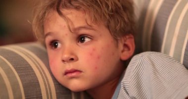 Baby toddler face watching TV screen at night on sofa at ngiht before bedtime