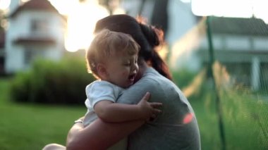 Anne gün batımında bebeği kucaklıyor. Ebeveyn teselli edici bebek kucağı