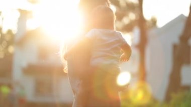 Mother holding baby infant outside during summer sunnset time
