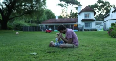 Baba, bebek oğluyla ev bahçesinde bağ kuruyor.