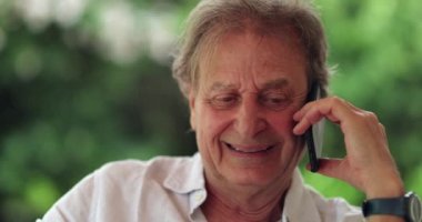 Happy older man speaking with friend on cellphone