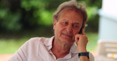 Older man talking on the phone. Candid authentic real life senior person talking on smartphone