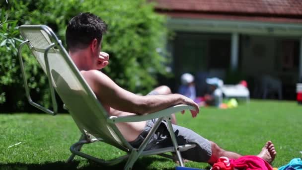 남자가 뒷마당에서 쉬면서 휴식을 취하고 있습니다 정원을 내려다 — 비디오