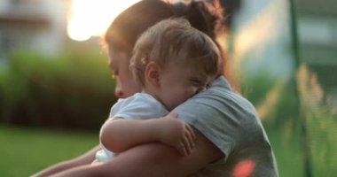 Anne üzgün bebeğe bakıyor. Anne, bebeği dışarıda teselli ediyor.