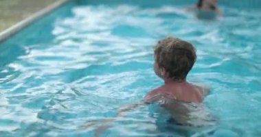 Çocuk çocuk havuzda hoplayıp zıplıyor.