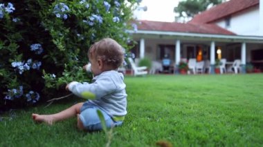Bebek bahçeyi keşfediyor. Evin arka bahçesinde tatlı bir bebek var.