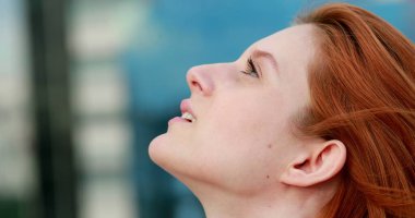 Gökyüzüne inançla bakan genç bir kadın yüzü