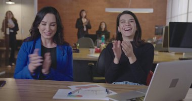 Bir grup ofis çalışanı alkışlıyor ve gülümsüyor. Mutlu insanlar iş yerinde başarıyı kutluyor. Meslektaşların POV 'u başarılı başlangıç yemeğini kutluyor