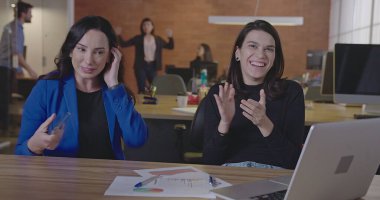 Bir grup ofis çalışanı alkışlıyor ve gülümsüyor. Mutlu insanlar iş yerinde başarıyı kutluyor. Meslektaşların POV 'u başarılı başlangıç yemeğini kutluyor