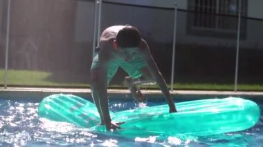 Kid standing on top of inflatable mattress keeping balance and having fun