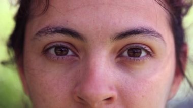 Woman face in 30s looking to camera. Closeup of person eyes staring