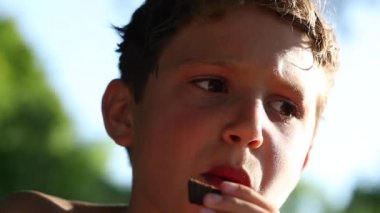 Contemplative young boy eating cookie outside