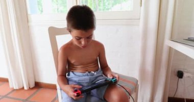 Video oyunu oynayan küçük çocuk kumanda ve joystick 'i tutuyor.