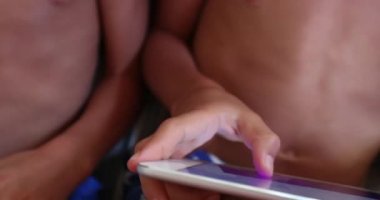 Mutlu çocuklar evde kanepede oturmuş tablet cihazıyla oyun oynuyorlar.