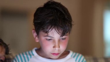 Geceleri tablet ekranı kullanan bir çocuk. Mavi ışık aygıtına bakan çocuk