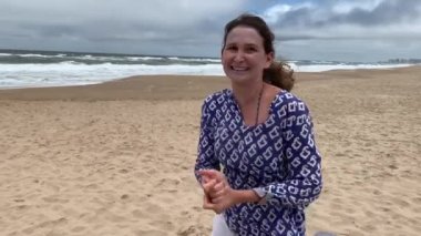 Kumsalda kendiliğinden dans eden mutlu bir kadın.