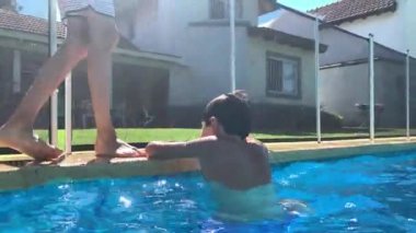 Çocuk havuzdan çıkıyor, çocuk kendini havuz kenarından kaldırıyor.