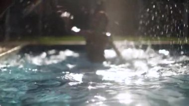 Çocuk suya atlıyor. Yüzme havuzu arka bahçe ortamı