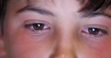Child boy eyes looking at tablet device screen. Kid staring at blue light macro eye close-up