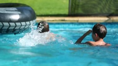 İki çocuk yaz günü arka bahçede yüzme havuzunda eğleniyor.