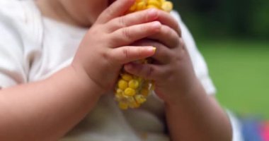 Child baby eating corn cob outside taking a bite of healthy eating