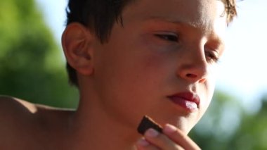 Handsome child eating cookie outdoors. Pensive close-up kid face outside