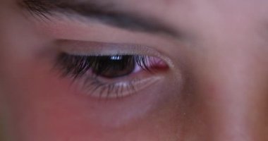 Child eyes looking at device screen. Young boy red eye staring at blue light glow at night