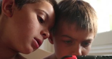 Video oyunu ekran aygıtı tarafından emilen çocuklar. Küçük çocuk internette oyun oynuyor, kardeşi oyun oynarken izliyor.