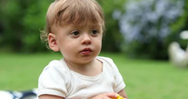 Portrait of adorable cute baby infant boy. Toddler taking a bite of corn outdoors
