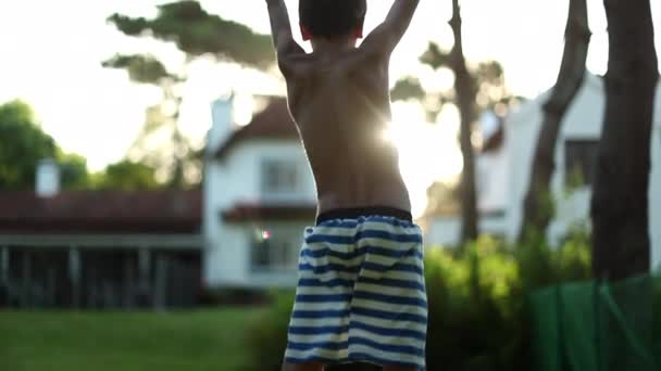 少年は喜んで空気中をジャンプします 太陽の光の中で勝利の空気中で拳を上げる子黄金の時間日没時間 — ストック動画