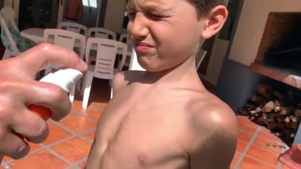 Pai Pulverizando Protetor Solar Loção Para Criança Menino Peito — Vídeo de Stock