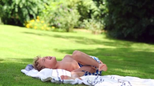 外の草の上に寝そべっている子供 — ストック動画