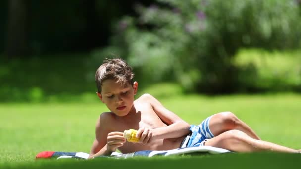 Young Boy Lying Grass Eating Corn Cob Snack Outdoors Child — Vídeo de stock