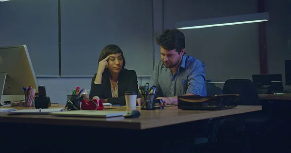 Frustrated business man and woman working late at night in the office workplace alone. People working late in the evening over time. Annoyed staff being overwhelmed by bureaucracy