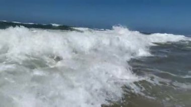 Deniz dalgalarıyla oynayan çocuklar çarpışıyor. Sahildeki dalgalara dalan çocuk