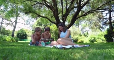 Anne ve çocuklar arka bahçede masal kitabı okuyorlar.