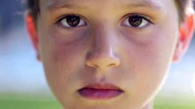Serious child boy looking to camera portrait. Kid staring to viewer outdoors